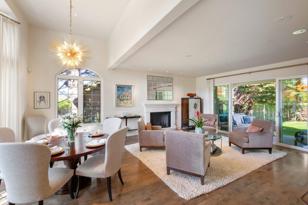 This is an example of a large classic formal open plan living room in San Francisco with white walls, medium hardwood flooring, a standard fireplace, a plastered fireplace surround, brown floors and a vaulted ceiling.