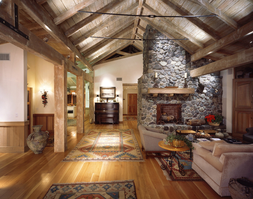 Rustikales Wohnzimmer mit braunem Holzboden, Kamin und Kaminumrandung aus Stein in Santa Barbara
