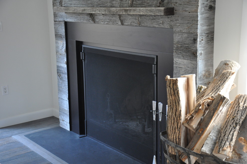 ニューヨークにあるお手頃価格の中くらいなインダストリアルスタイルのおしゃれなLDK (白い壁、濃色無垢フローリング、標準型暖炉、木材の暖炉まわり、壁掛け型テレビ) の写真