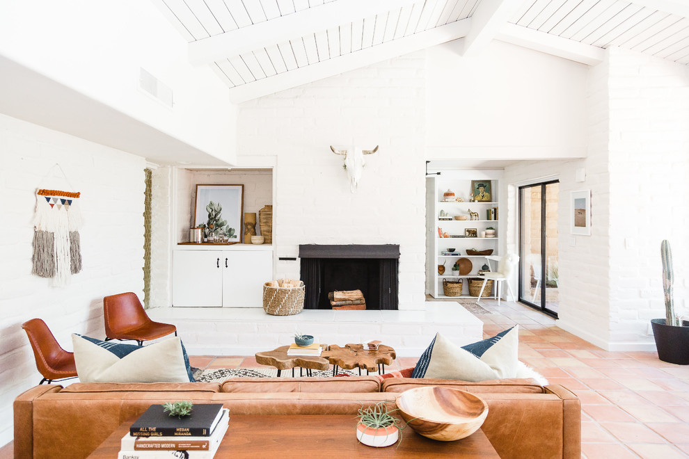 Living room in San Diego with white walls, a standard fireplace, a brick fireplace surround and orange floors.