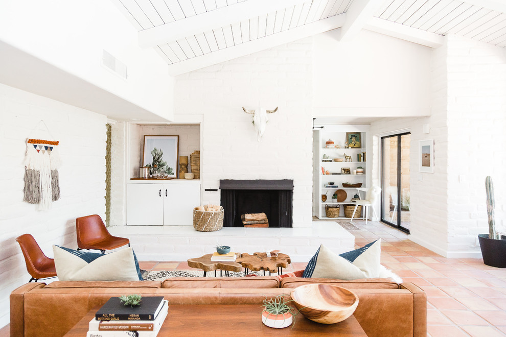 Example of a southwest orange floor living room design in San Diego with white walls, a standard fireplace and a brick fireplace