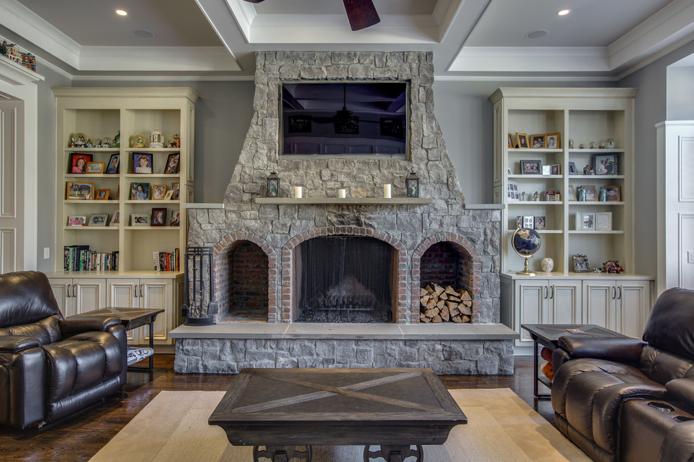 Medium sized rustic open plan living room in Chicago with grey walls, medium hardwood flooring, a standard fireplace, a stone fireplace surround, a wall mounted tv and brown floors.