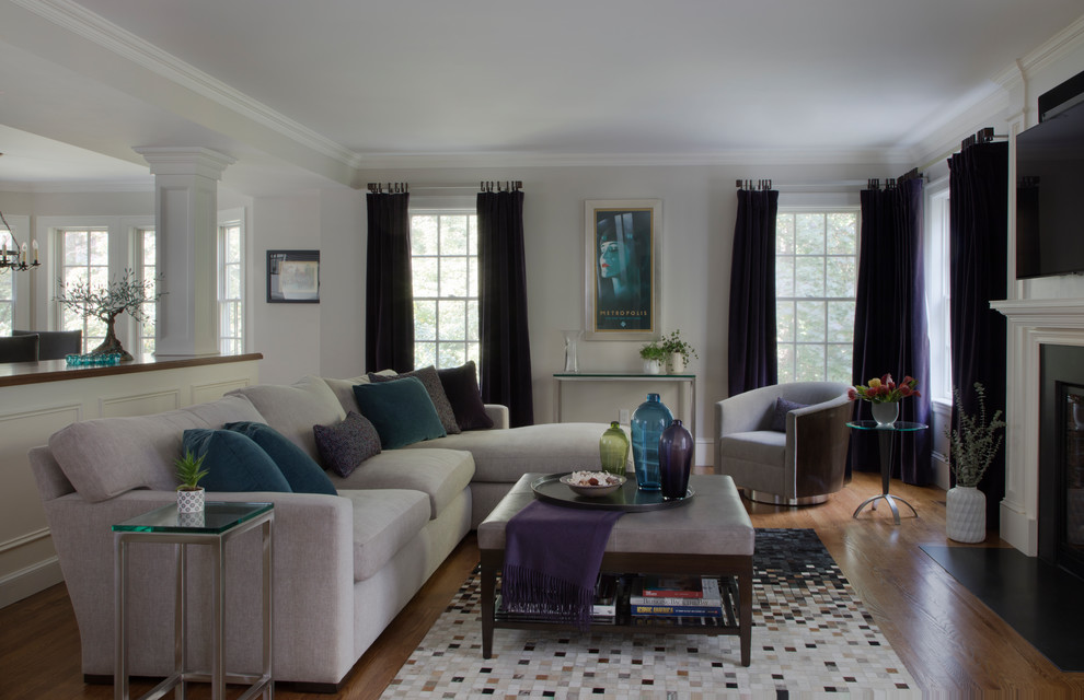 Großes Klassisches Wohnzimmer mit weißer Wandfarbe, braunem Holzboden, Kamin, Kaminumrandung aus Holz, TV-Wand und buntem Boden in Boston