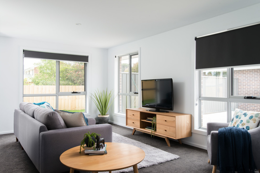 На фото: парадная, открытая гостиная комната среднего размера в современном стиле с белыми стенами, ковровым покрытием, отдельно стоящим телевизором и серым полом с