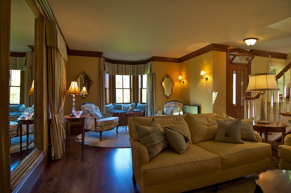 Modelo de salón para visitas abierto clásico con paredes amarillas y suelo de madera oscura