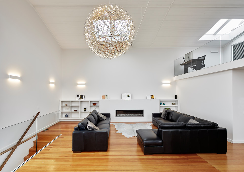 Modernes Wohnzimmer im Loft-Stil mit weißer Wandfarbe, braunem Holzboden, Gaskamin, verputzter Kaminumrandung und braunem Boden in Wellington