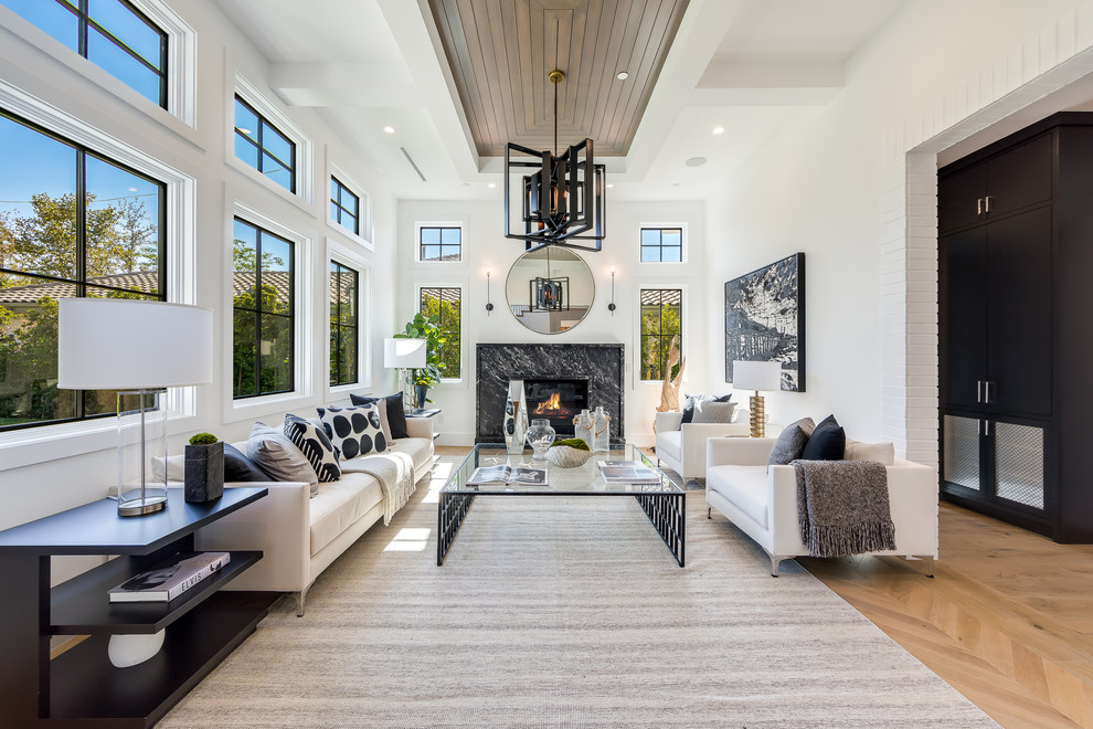 This is an example of a classic living room in Los Angeles with white walls, light hardwood flooring, a standard fireplace, a stone fireplace surround, beige floors and feature lighting.