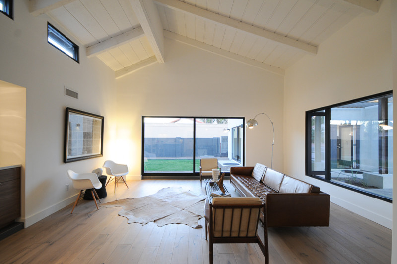Imagen de salón abierto retro grande con paredes blancas y suelo de madera clara