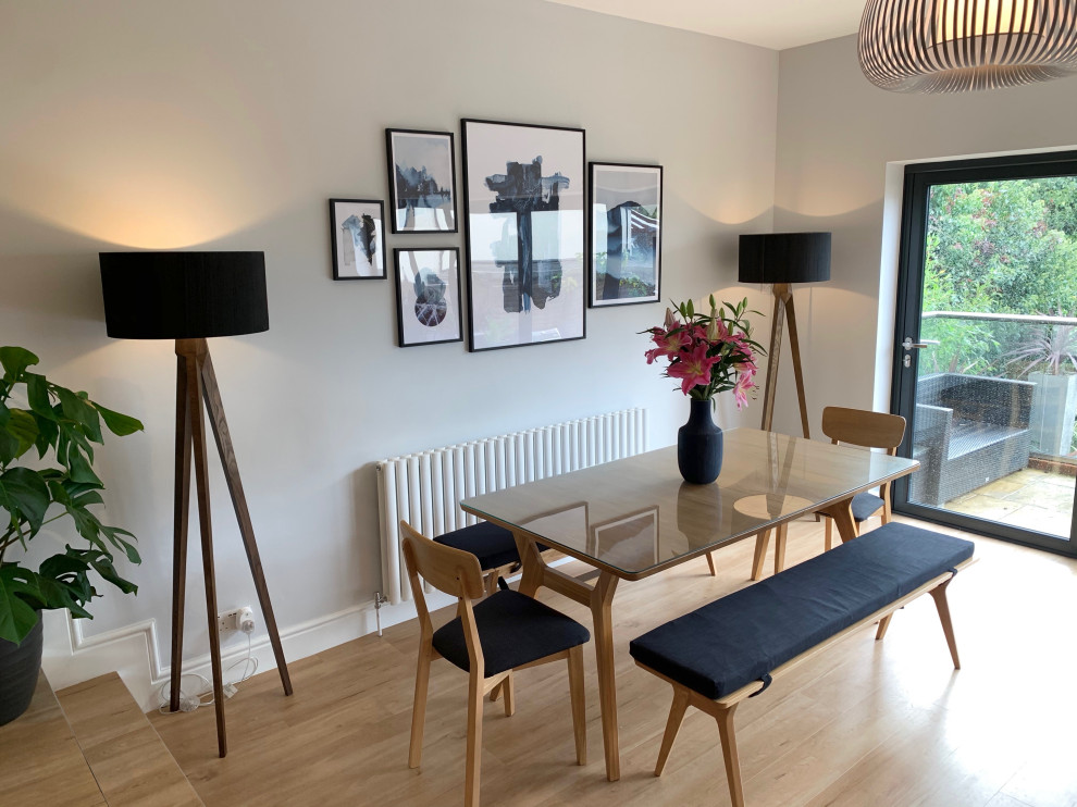 Large danish laminate floor dining room photo in Hertfordshire with gray walls, a wood stove and a plaster fireplace