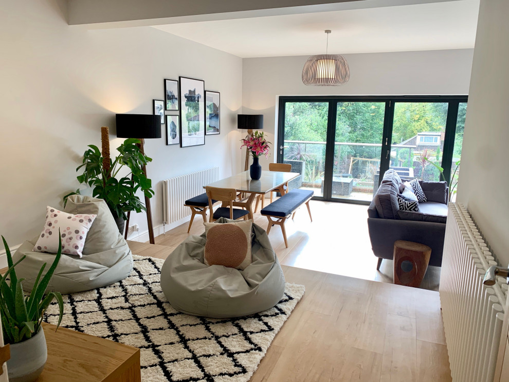 Large scandi open plan living room in Hertfordshire with a reading nook, grey walls, laminate floors, a wood burning stove, a plastered fireplace surround and a wall mounted tv.