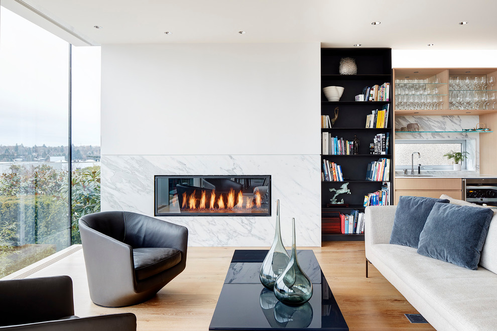 Offenes Modernes Wohnzimmer mit weißer Wandfarbe, hellem Holzboden, Kamin und Kaminumrandung aus Stein in Vancouver