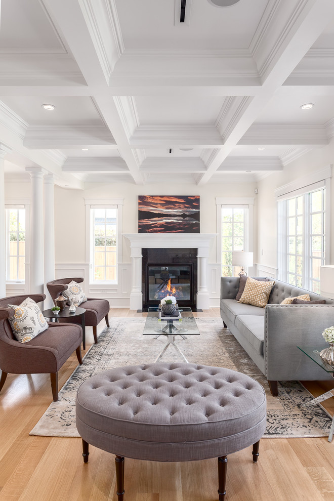 Photo of a large traditional formal open plan living room in Vancouver with white walls, medium hardwood flooring, a standard fireplace, a stone fireplace surround and no tv.