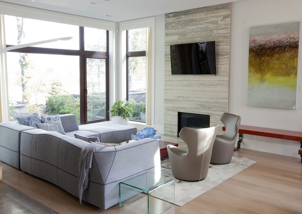 Modern inredning av ett vardagsrum, med vita väggar, mellanmörkt trägolv, en standard öppen spis, en spiselkrans i sten och en väggmonterad TV