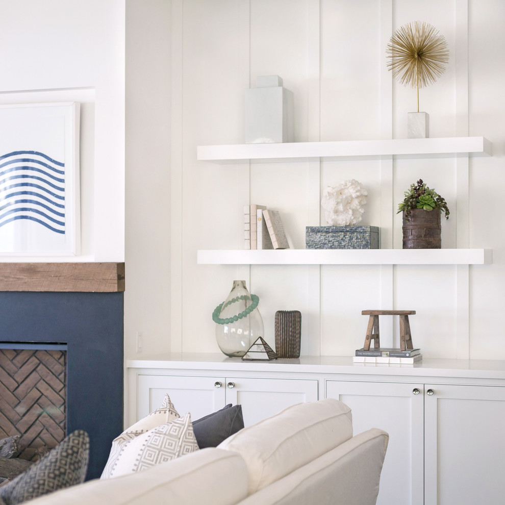Maritimes Wohnzimmer mit weißer Wandfarbe, braunem Holzboden und Kamin in Orange County