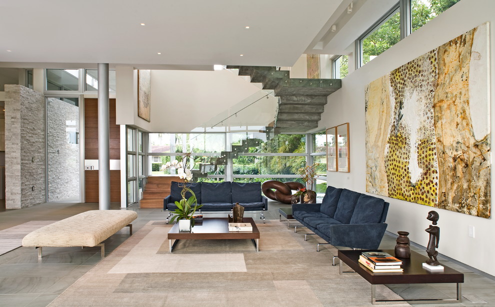 Стильный дизайн: гостиная комната в современном стиле с белыми стенами и синим диваном - последний тренд