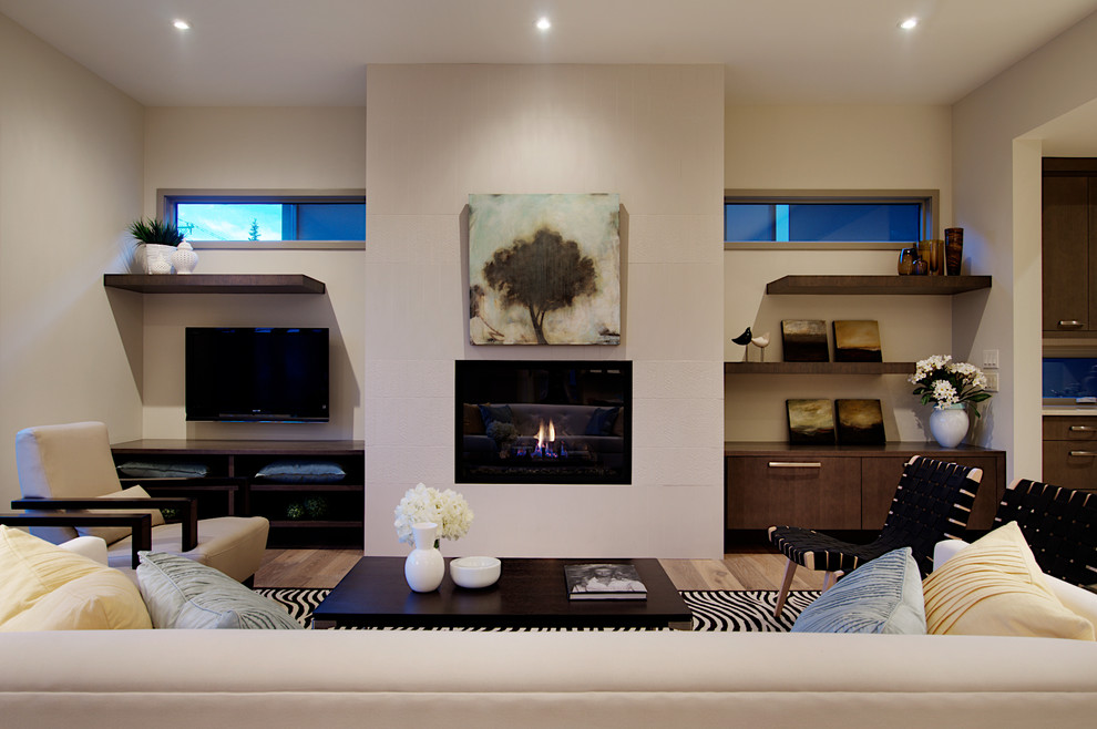 Imagen de salón moderno con paredes blancas, suelo de madera clara, televisor colgado en la pared y marco de chimenea de baldosas y/o azulejos