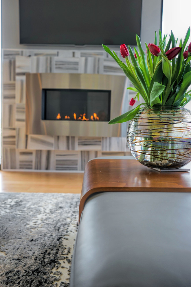 Cette image montre un salon minimaliste de taille moyenne et ouvert avec un mur gris, parquet clair, une cheminée ribbon, un manteau de cheminée en carrelage et un téléviseur fixé au mur.