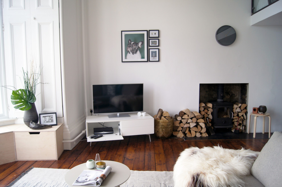 Exempel på ett mellanstort skandinaviskt allrum med öppen planlösning, med vita väggar, mörkt trägolv, en fristående TV och brunt golv