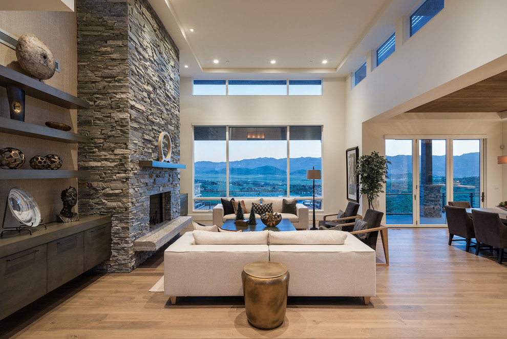 Living room - large contemporary open concept and formal medium tone wood floor living room idea in Salt Lake City with a standard fireplace, a stone fireplace, white walls and no tv