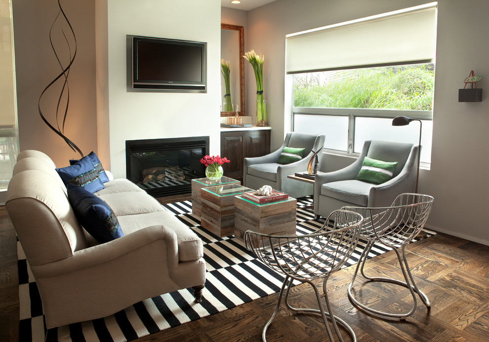 Foto di un grande soggiorno design stile loft con pareti grigie, parquet scuro, camino classico, cornice del camino in intonaco e TV a parete