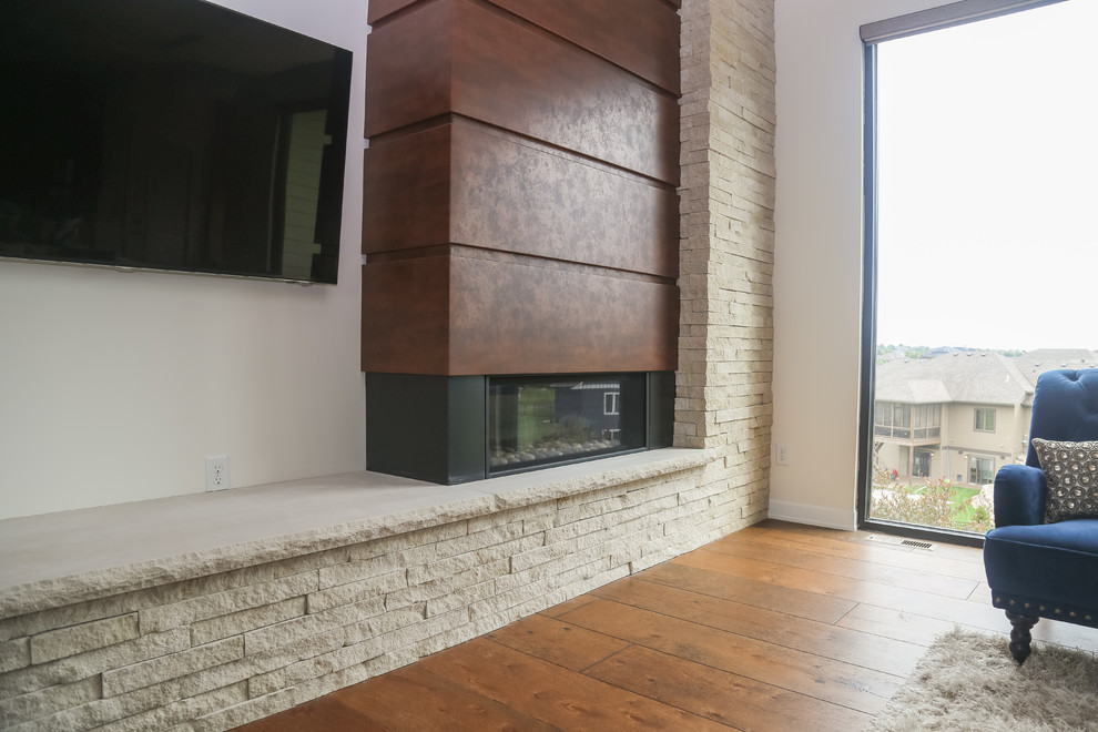 Imagen de salón abierto actual de tamaño medio con paredes blancas, suelo de madera en tonos medios, chimenea de esquina, marco de chimenea de piedra, televisor colgado en la pared y suelo marrón