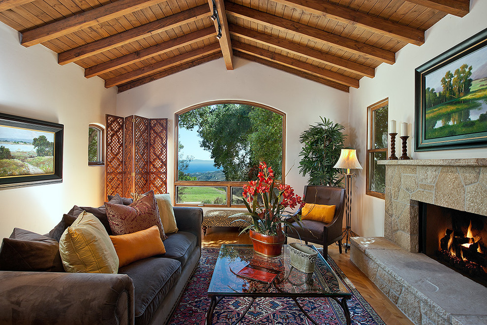 На фото: гостиная комната в стиле рустика с фасадом камина из камня и ковром на полу