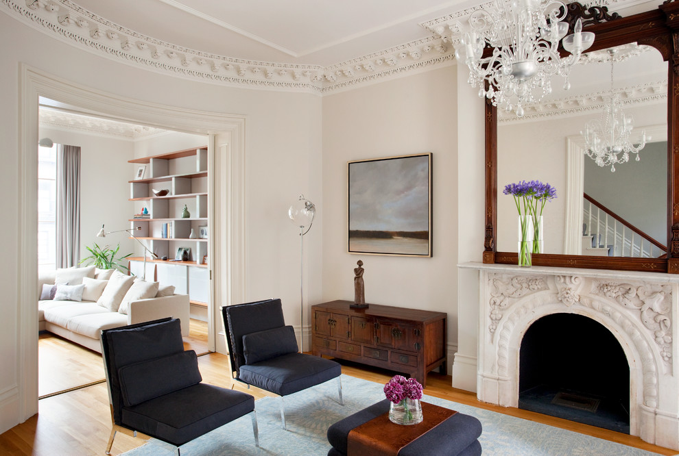 Diseño de salón para visitas minimalista con paredes beige, suelo de madera en tonos medios, todas las chimeneas y marco de chimenea de piedra