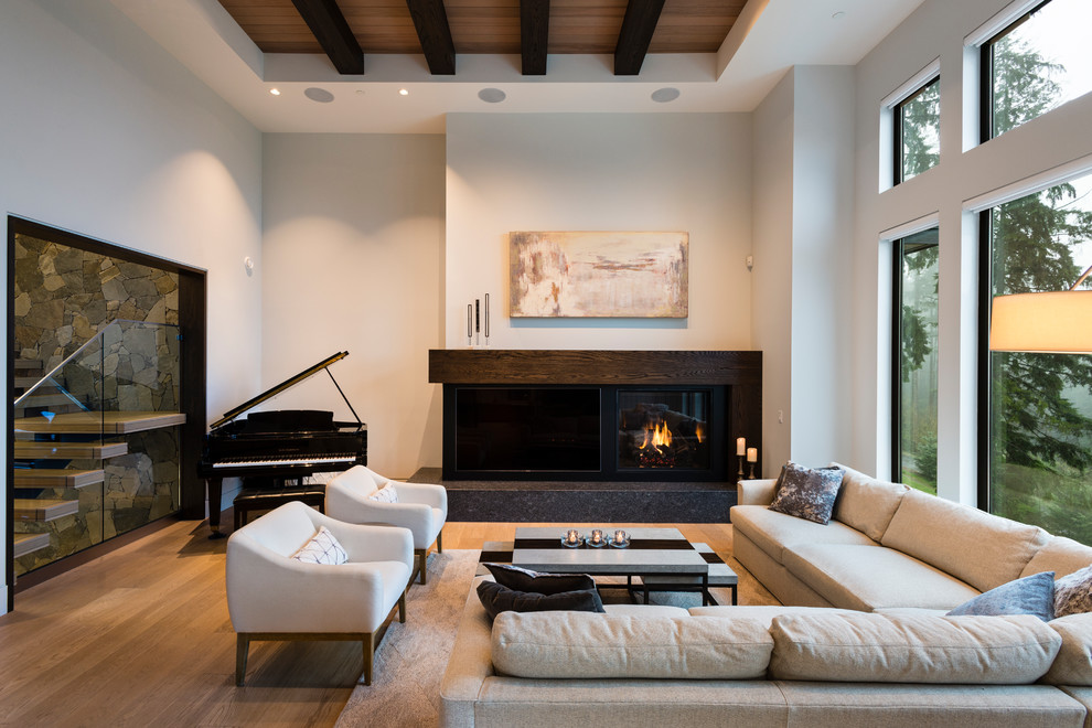 Exemple d'un grand salon chic ouvert avec un mur blanc, parquet clair, une cheminée standard, un manteau de cheminée en bois, un téléviseur encastré et un sol beige.