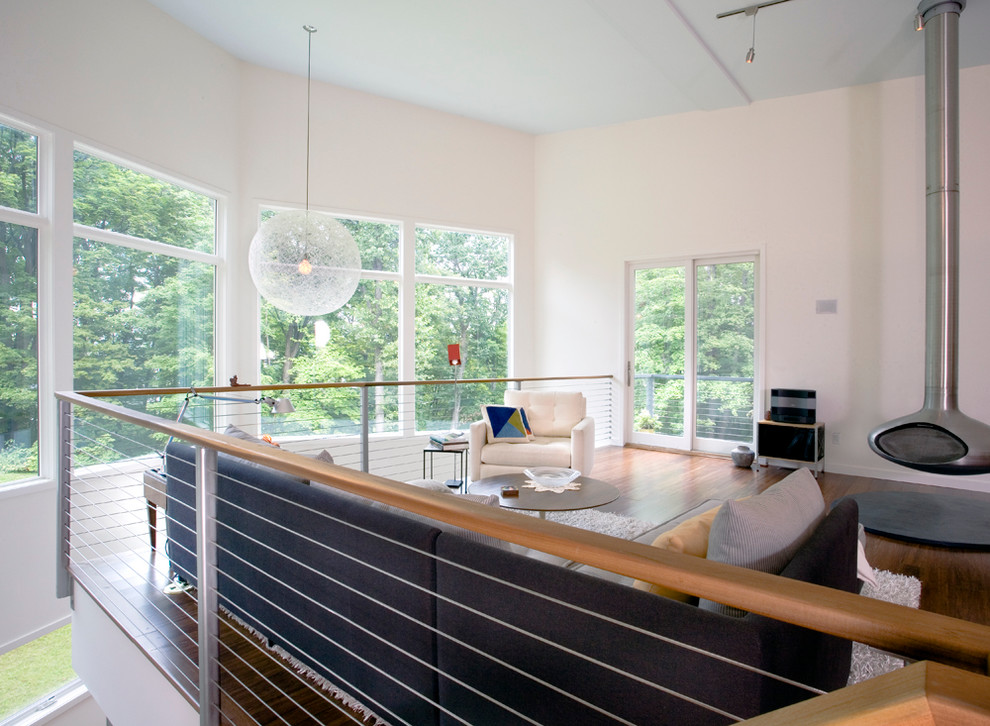 Imagen de salón tipo loft minimalista sin televisor con paredes blancas, suelo de madera oscura y chimeneas suspendidas