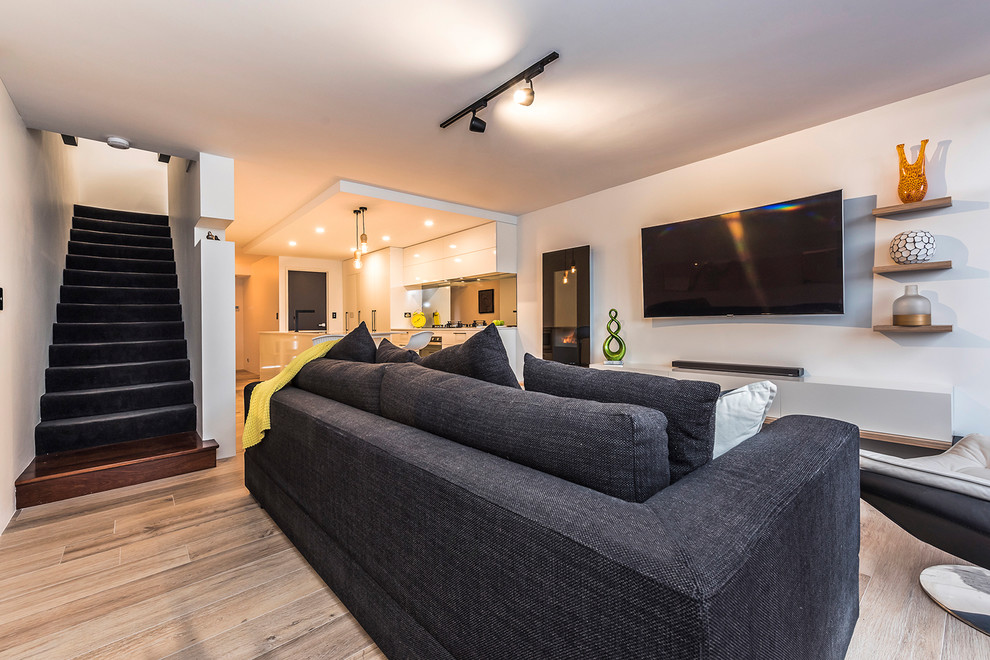Foto di un soggiorno design di medie dimensioni e aperto con pareti bianche, pavimento in gres porcellanato e TV a parete