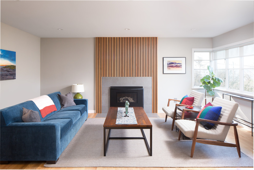 Contemporary living room in Seattle with beige walls, a standard fireplace, a metal fireplace surround, brown floors and light hardwood flooring.