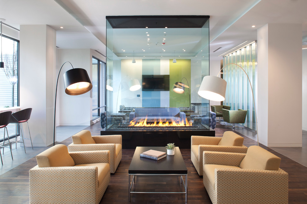 Cette image montre un grand salon design ouvert avec une cheminée double-face, un téléviseur fixé au mur et éclairage.