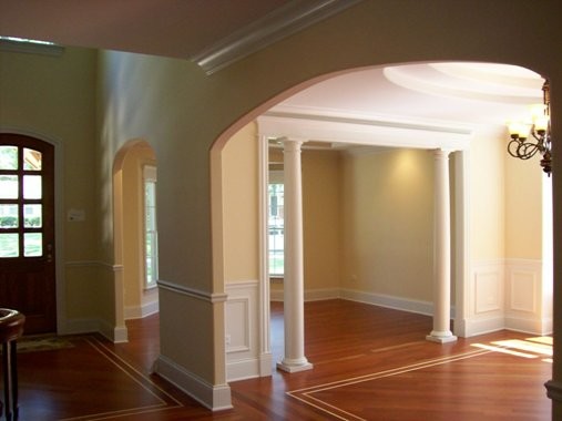 Aménagement d'un grand salon classique ouvert avec une salle de réception, un mur jaune et un sol en bois brun.