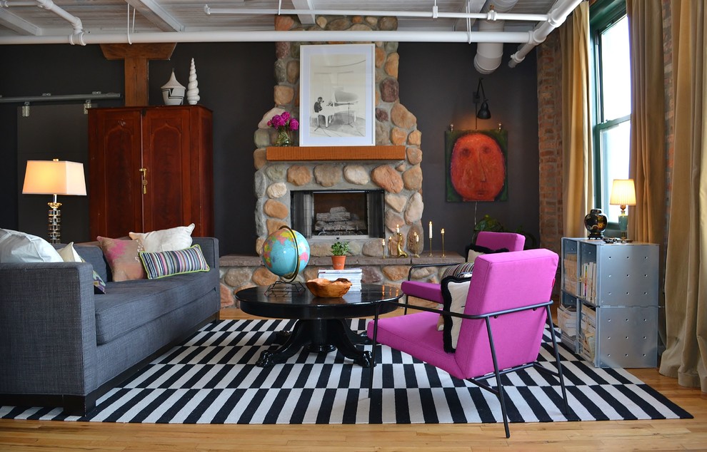 Foto di un soggiorno eclettico con pareti nere, pavimento in legno massello medio, camino classico, cornice del camino in pietra e nessuna TV