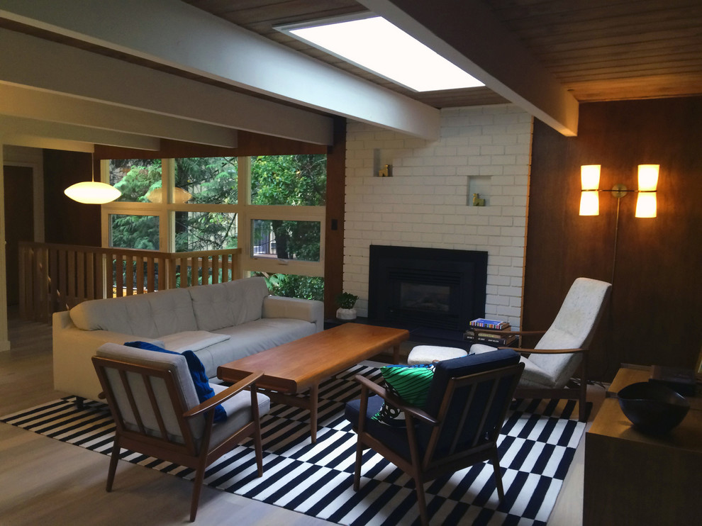 Example of a mid-sized 1960s enclosed medium tone wood floor living room design in Vancouver with brown walls, a standard fireplace, a brick fireplace and a wall-mounted tv