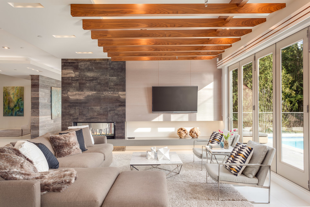 Стильный дизайн: гостиная комната в современном стиле с двусторонним камином и телевизором на стене - последний тренд