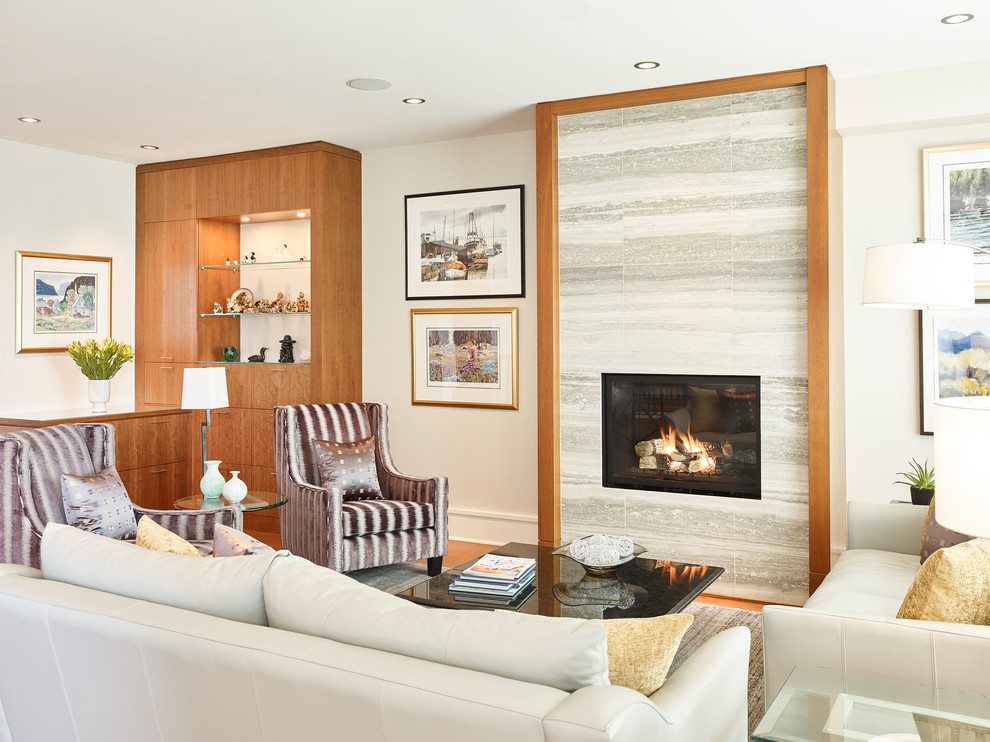 Inspiration pour un grand salon design ouvert avec un mur gris, un sol en bois brun, une cheminée standard, un manteau de cheminée en pierre et un sol marron.