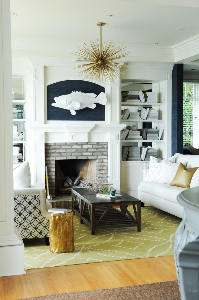 This is an example of a medium sized beach style open plan living room in Vancouver with blue walls, light hardwood flooring, a standard fireplace, a brick fireplace surround, a reading nook, no tv and brown floors.