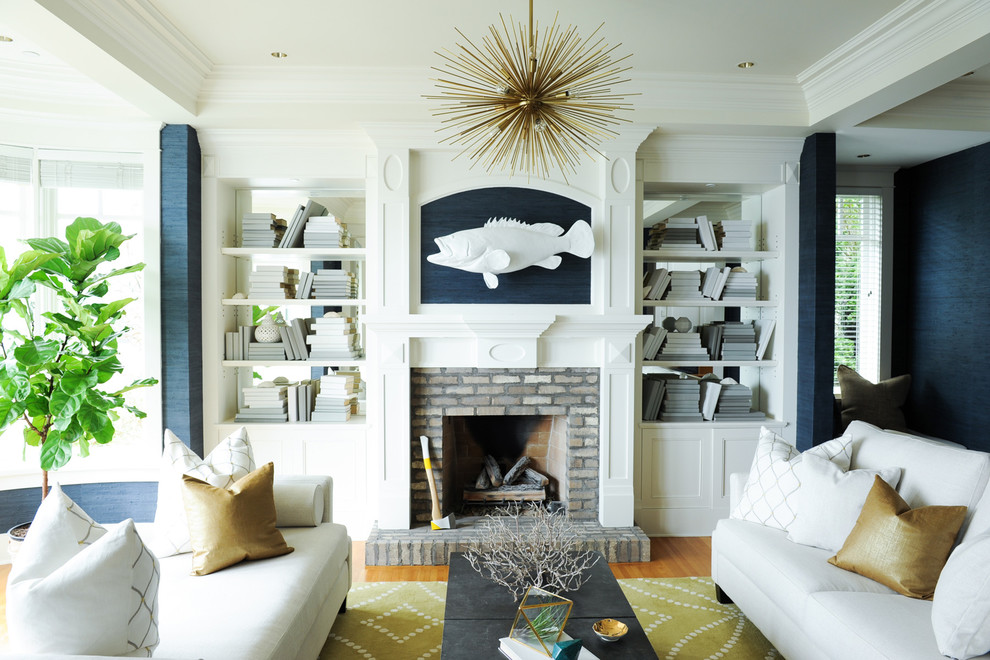 Inspiration for a medium sized beach style open plan living room in Vancouver with a reading nook, blue walls, light hardwood flooring, a standard fireplace, a brick fireplace surround, no tv and brown floors.