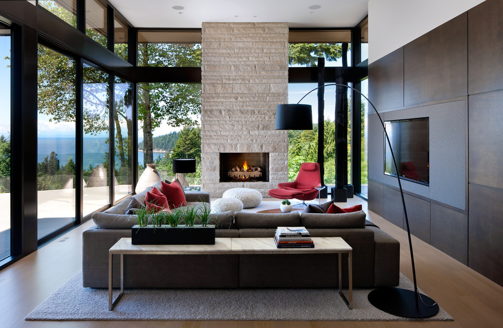 Exemple d'un grand salon moderne ouvert avec un téléviseur encastré, un sol beige, un sol en bois brun, une cheminée standard et un manteau de cheminée en pierre.