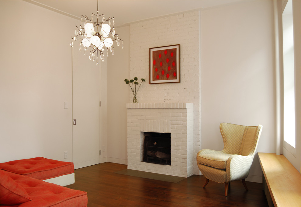 Small contemporary living room in New York with white walls, a standard fireplace, a brick fireplace surround, no tv and dark hardwood flooring.