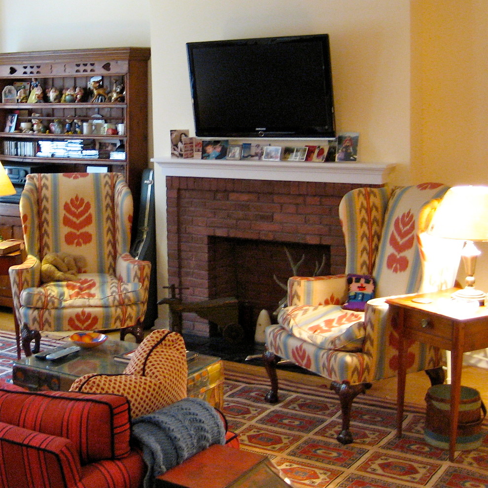 Inredning av ett amerikanskt mellanstort vardagsrum, med beige väggar, en standard öppen spis, en spiselkrans i tegelsten, en väggmonterad TV, beiget golv och ljust trägolv