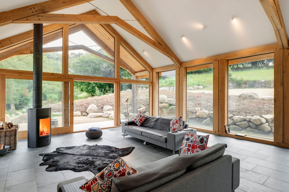This is an example of a large contemporary formal open plan living room in Devon with white walls, light hardwood flooring and a wood burning stove.