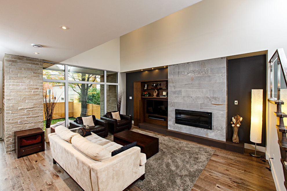 This is an example of a large contemporary open plan living room in Ottawa with grey walls, medium hardwood flooring, a ribbon fireplace, a tiled fireplace surround and a wall mounted tv.
