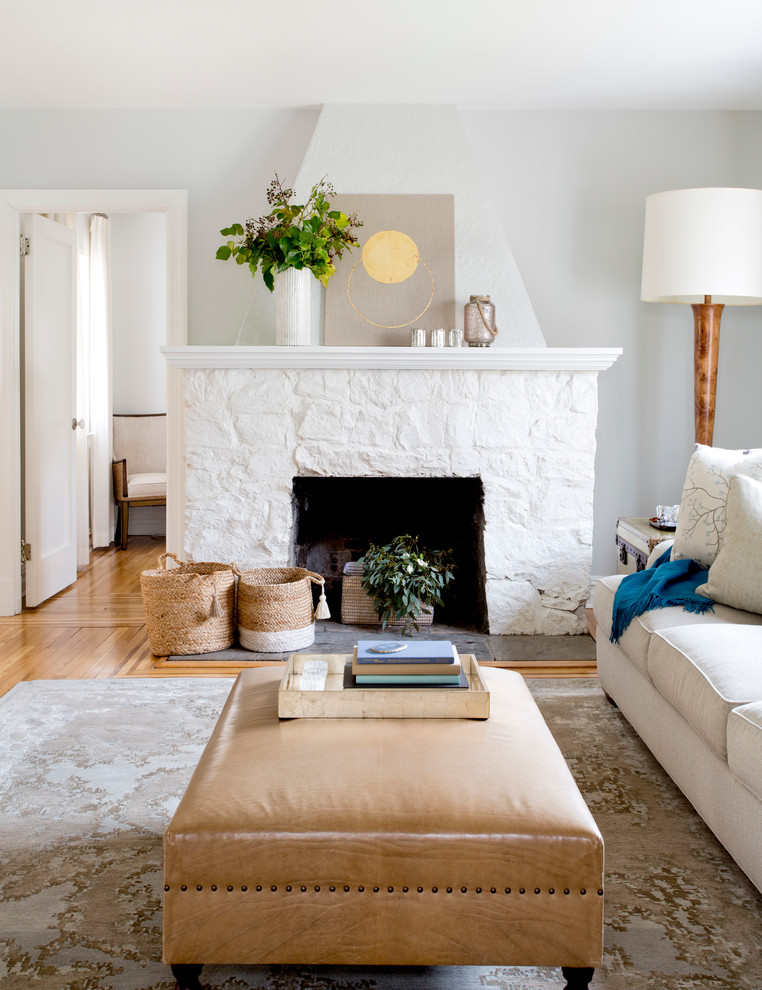 Inspiration pour un salon traditionnel de taille moyenne et fermé avec un sol en bois brun, une cheminée standard, un manteau de cheminée en pierre, un téléviseur indépendant et un mur gris.