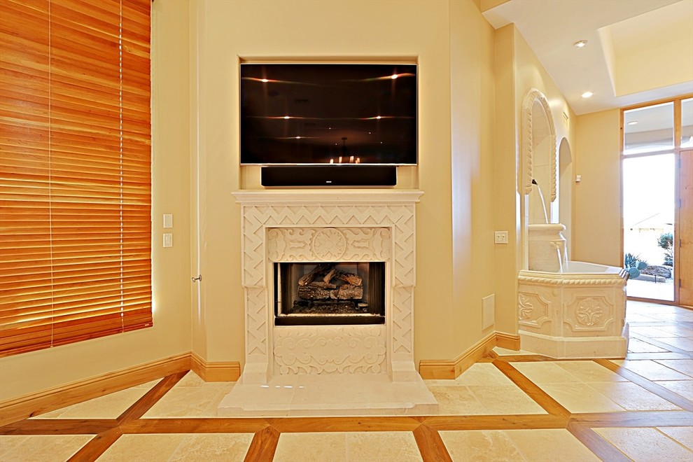 Imagen de salón abierto de estilo americano grande con paredes beige, suelo de travertino, todas las chimeneas, marco de chimenea de piedra y televisor colgado en la pared