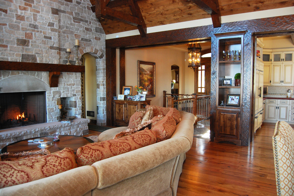 Photo of a large rustic open plan living room in Minneapolis with beige walls, light hardwood flooring, a standard fireplace, a stone fireplace surround and a built-in media unit.