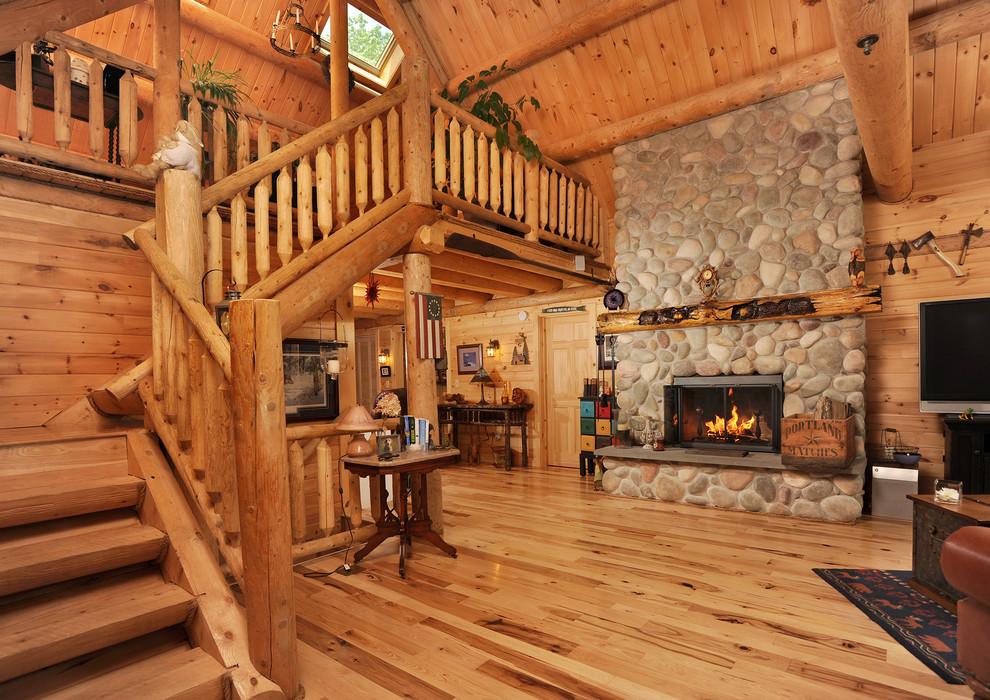 Cette photo montre un grand salon montagne ouvert avec un sol en bois brun, une cheminée standard, un manteau de cheminée en pierre et un téléviseur indépendant.