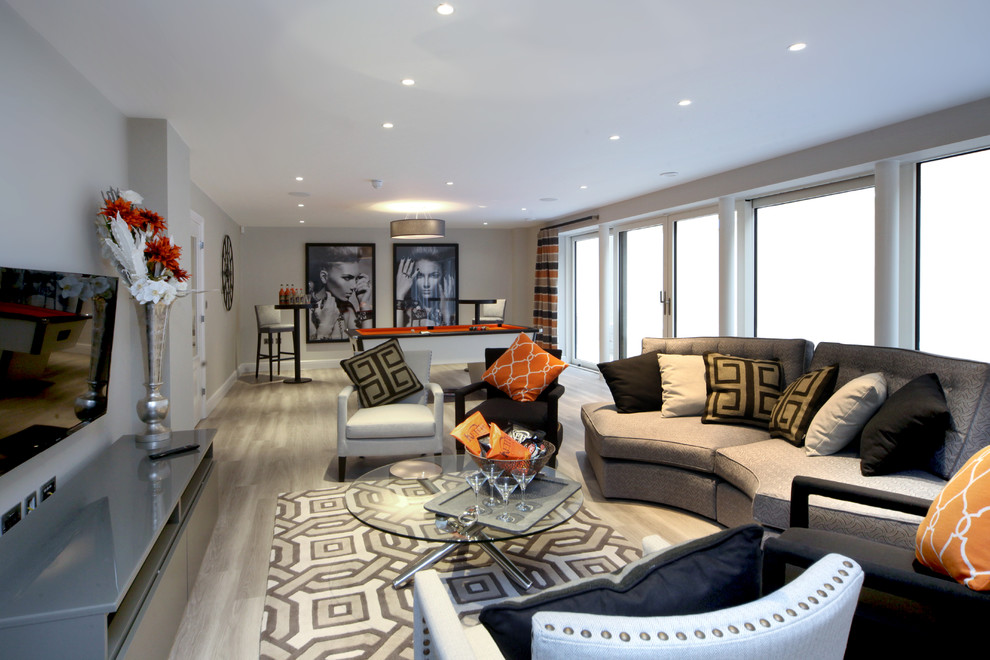 Идея дизайна: открытая гостиная комната в современном стиле с серыми стенами, светлым паркетным полом и телевизором на стене без камина