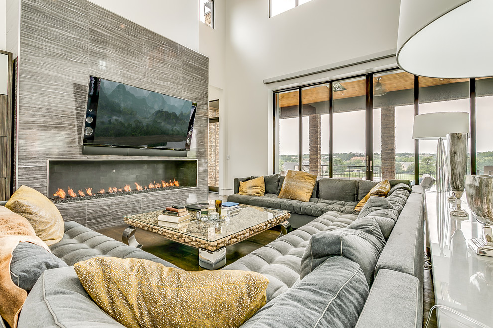 Diseño de salón abierto actual con paredes grises, televisor colgado en la pared y chimenea lineal
